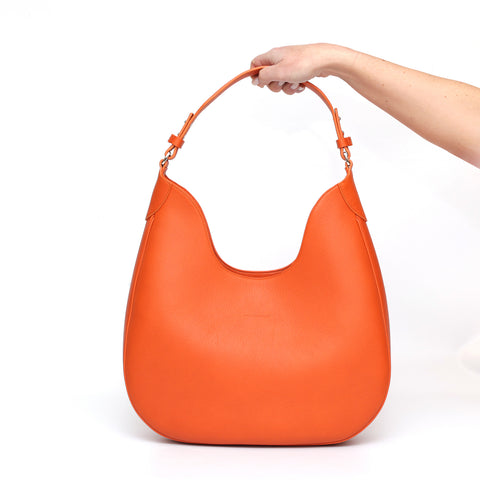 Cloe, borsa da spalla in morbida pelle martellata arancio, design a sacca con accessori metallici color argento, firmata Pianigiani Bags.