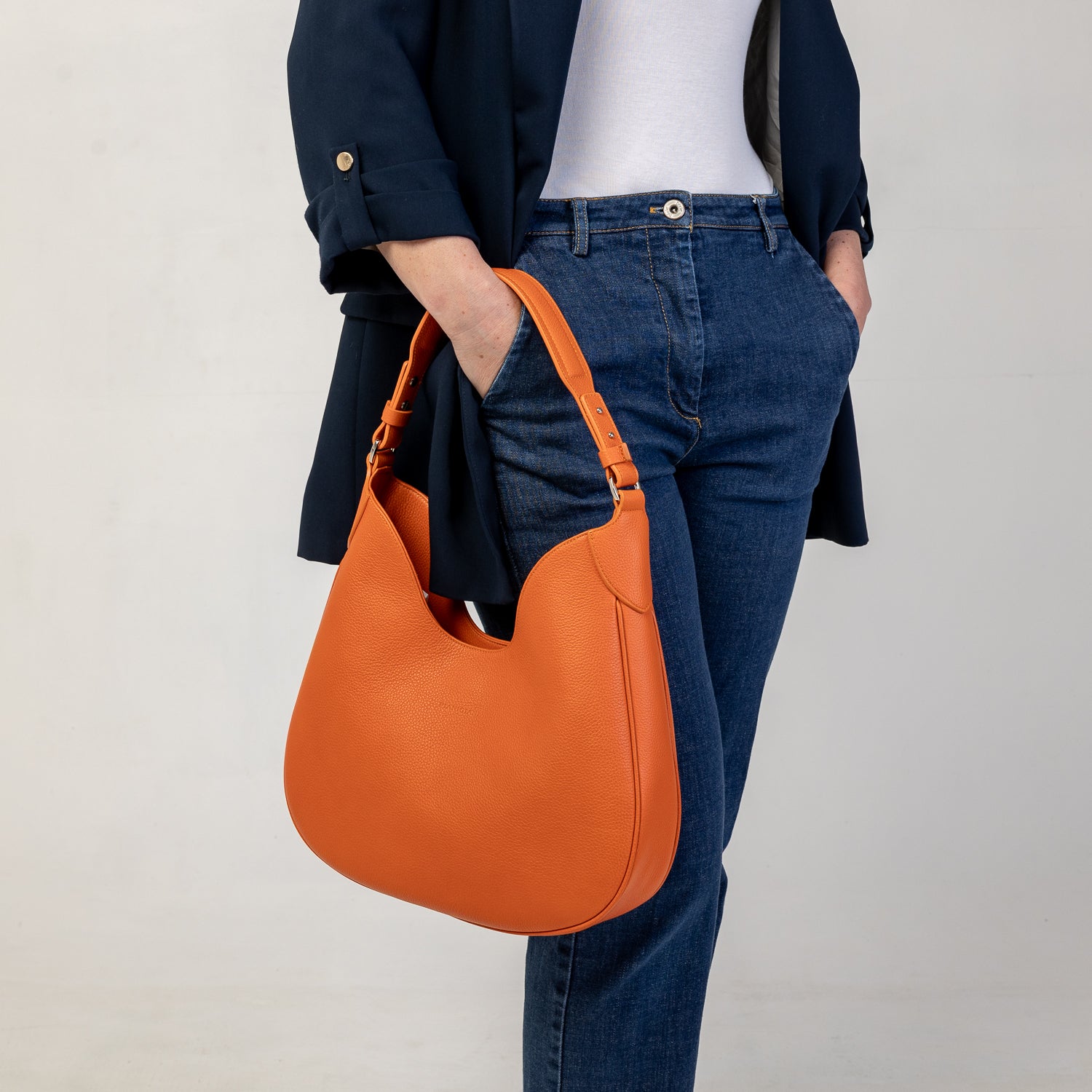 Cloe piccola, borsa da spalla in morbida pelle martellata arancio, design a sacca con accessori metallici color argento, firmata Pianigiani Bags.