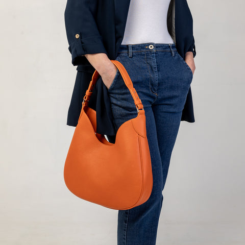 Cloe piccola, borsa da spalla in morbida pelle martellata arancio, design a sacca con accessori metallici color argento, firmata Pianigiani Bags.