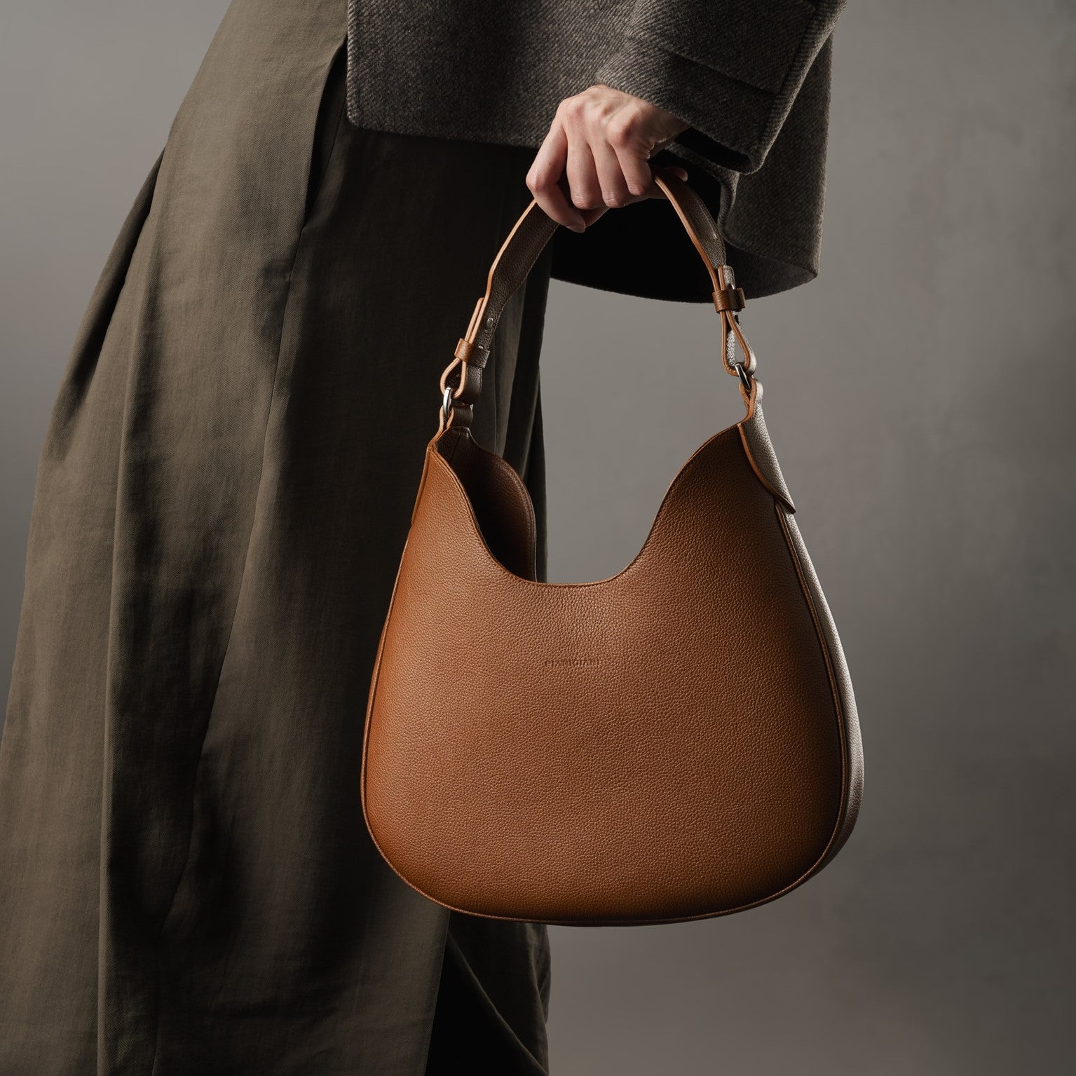 Cloe, borsa da spalla in morbida pelle martellata marrone, design a sacca con accessori metallici color argento, firmata Pianigiani Bags.