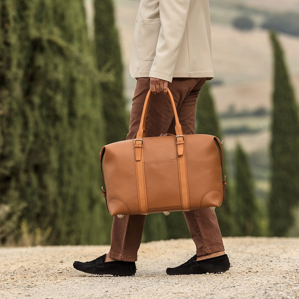 Borsone da viaggio taglia small, in pelle martellata marrone caramello e rifiniture in cuoio naturale, doppi manici a mano e tracolla regolare removibile. La fodera interna è in cotone beige. Prodotto da Pianigiani handmade leather bags in Italia.